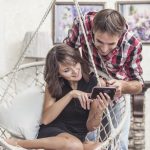 Couple man and woman with smartphone at home on the chair swing