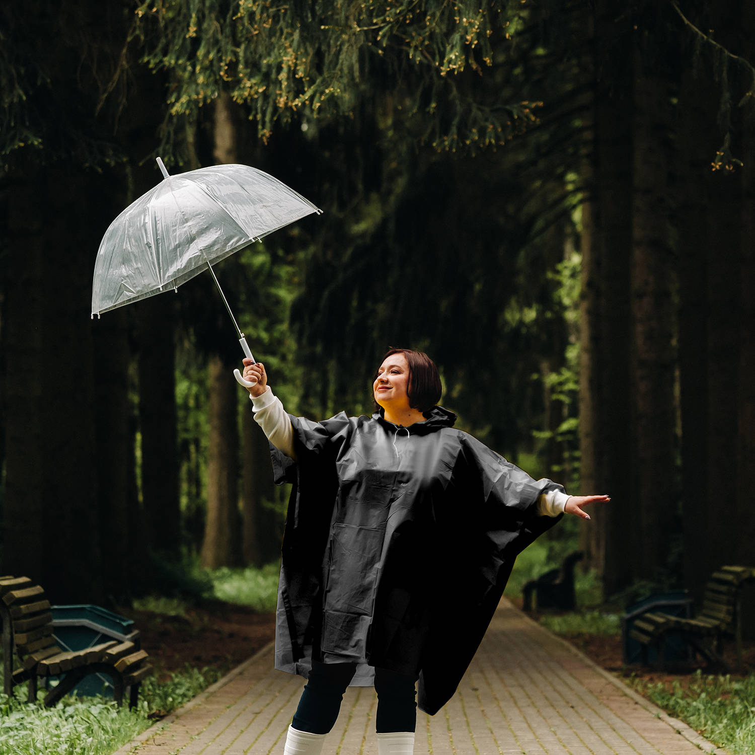 a woman in a yellow raincoat and an umbrella walks in the park and garden in summer