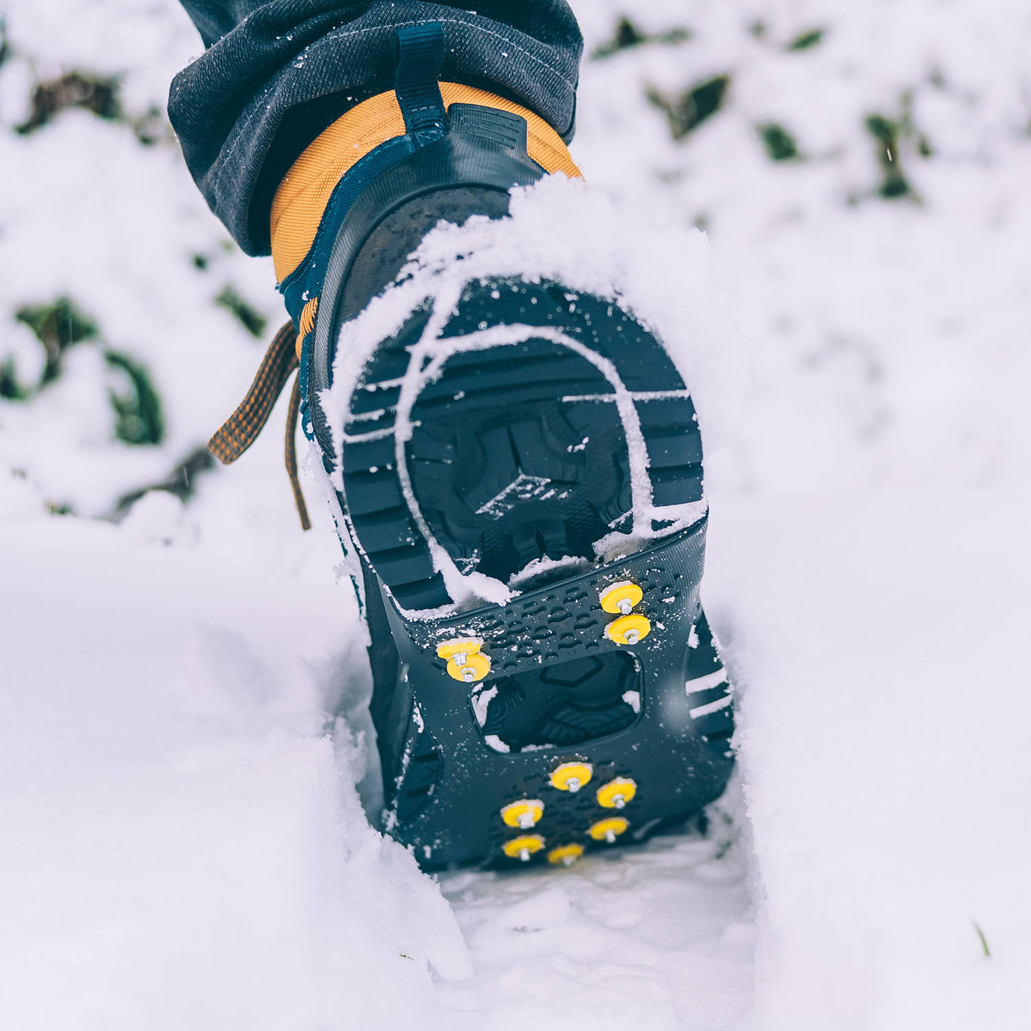 The man has ice shoes on his shoes. A people walks in the snow in winter.