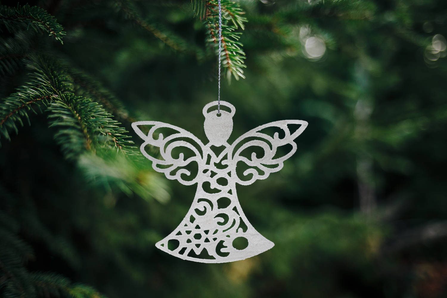 Closeup of a wooden snowflake-shaped Christmas ornament on a pine tree