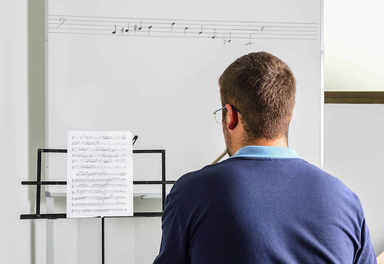 Young student studies lesson on sheet music in the classroom.