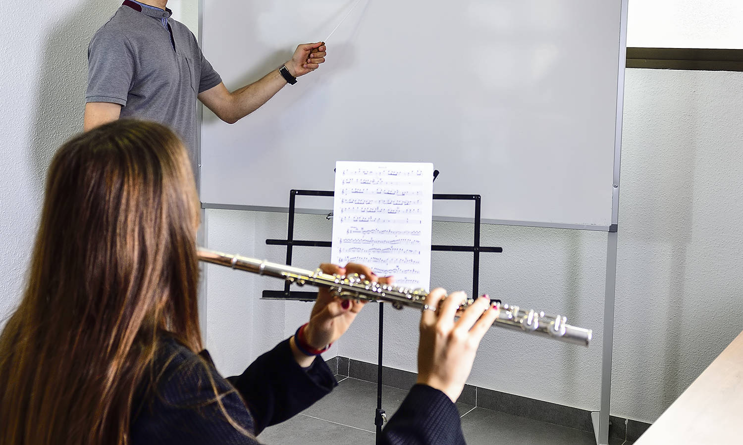 Teacher corrects music in the classroom, to a young student